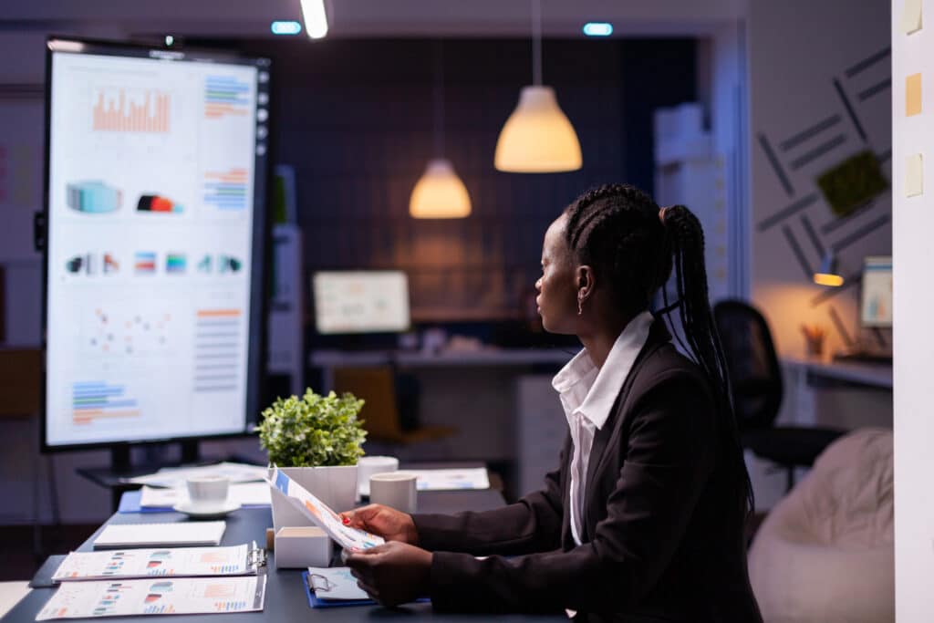 Image of an African American woman working with data on a computer in an office setting.