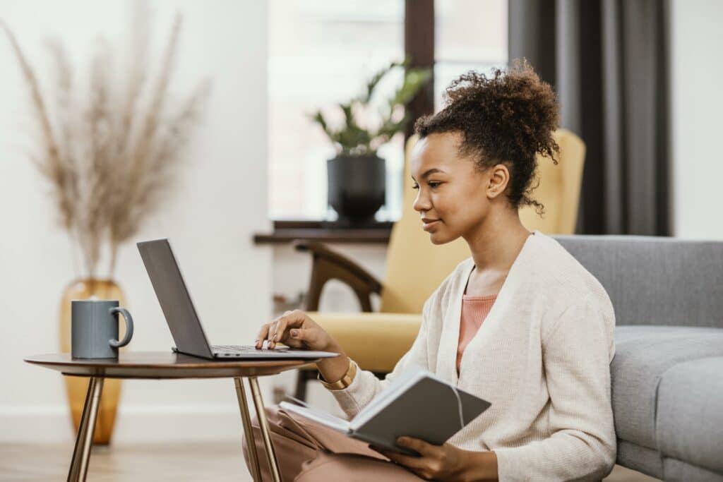Young woman sitting in her lounge and using her laptop to find work. 